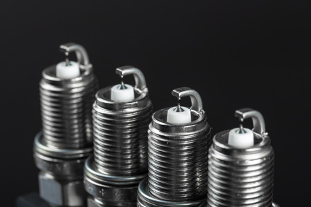 A set of new spark plugs of the car, and spare parts of vehicles on a dark  background. Studio macro image of high quality. To advertise auto service.の写真素材