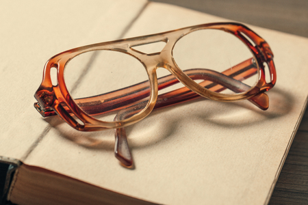 old book open on a wooden table with glassesの写真素材