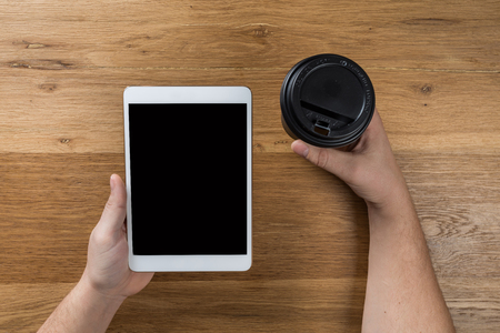 Hand touch on empty screen of tablet above brown table top view, Leave space for display of your content, Technology concept, mock up for montage your contentの写真素材