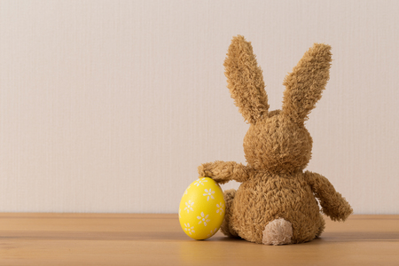 Easter bunny rabbit with  painted egg on wooden background. Easter holiday concept.の写真素材