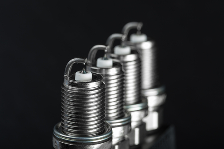 A set of new spark plugs of the car, and spare parts of vehicles on a dark  background. Studio macro image of high quality. To advertise auto service.の写真素材