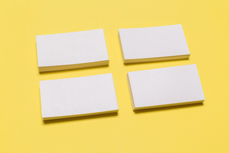 Blank white business cards on yellow background. Mockup for branding identity. Template for graphic designers portfolios. Top view.の写真素材