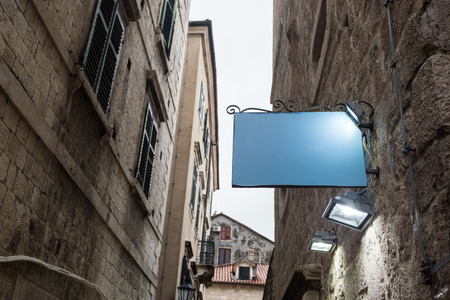 shape traditional bar signage mockup in old city center. blank mockup outdoor advertising with copy spaceの写真素材