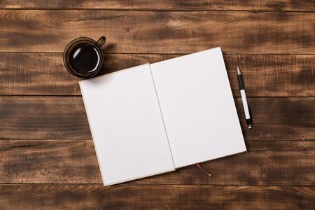 top view image of open notebook with blank pages next to cup of coffee on wooden table. ready for adding text or mockup.の写真素材