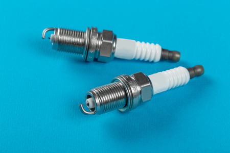 A set of new spark plugs a blue background. Studio macro image of high quality. To advertise auto...