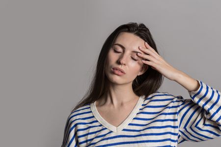 A pretty woman with fluffy hair, dressed casually. Studio shot of a lovely beautiful woman isolated against an empty gray studio wall.の写真素材