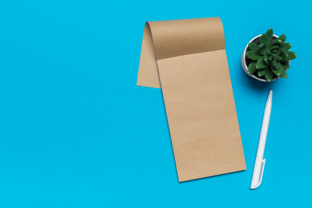Blank paper notebook on blue background.Office desk table concept.