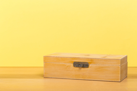 Antique old handmade casket on wooden table with color wall backgroundの写真素材