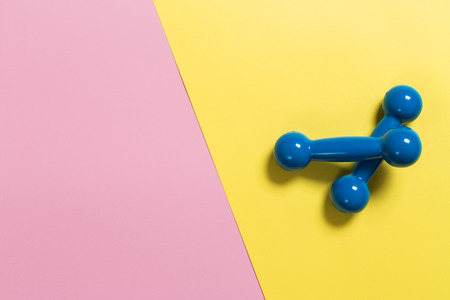 Styled photography of fitness equipment dumbbells on pink and yellow background. Flat lay.の写真素材