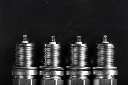 A set of new spark plugs of the car, and spare parts of vehicles on a dark  background. Studio macro image of high quality. To advertise auto service.の写真素材