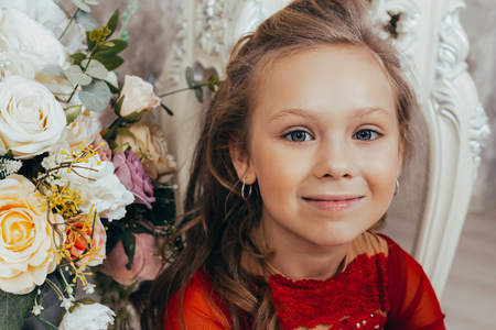 portrait of a smiling young girl in a red dress and with a beautiful hairstyle against the background of a grunge wallの写真素材