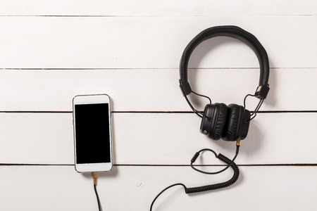 black Headphones with Smartphone on white wooden backgroundの写真素材