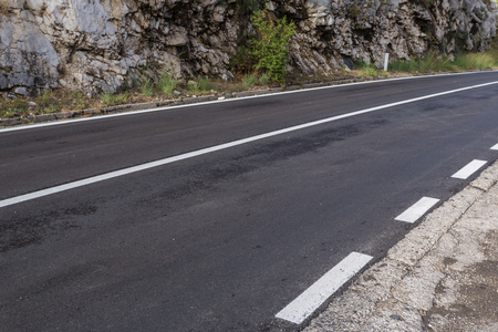 Asphalt road. Landscape with rocks, sunny sky with clouds and beautiful mountain road with white linesの写真素材
