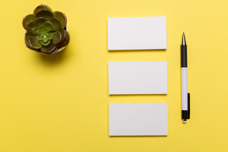 Blank white business cards on yellow background. Mockup for branding identity. Template for graphic designers portfolios. Top view. の写真素材