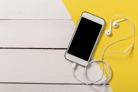 Headphones and smartphone on wooden background.Trendy colorful photo. Minimal style with colorful paper backdrop. Music conceptの写真素材