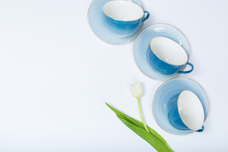 Clean dishes, coffee or tea set. Plenty of elegant porcelain cups and saucers with flower inside at white background, high key, top view and flat lay.の写真素材
