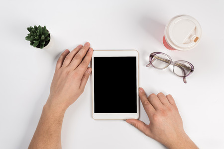 Hand touch on empty screen of tablet above brown table top view, Leave space for display of your content, Technology concept, mock up for montage your contentの写真素材