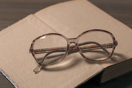 old book open on a wooden table with glassesの写真素材