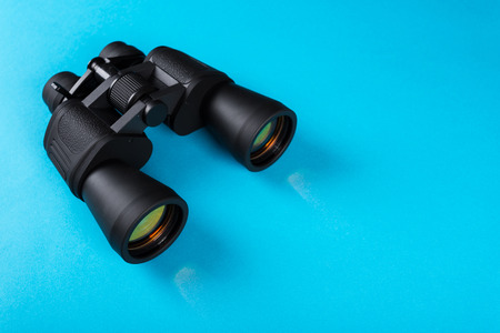 Black binoculars with orange lens on blue backgroundの写真素材