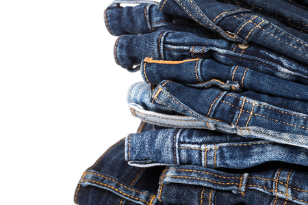 stack of various shades of blue jeans on white backgroundの写真素材