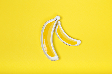 banana-like plate on yellow background. conceptの写真素材