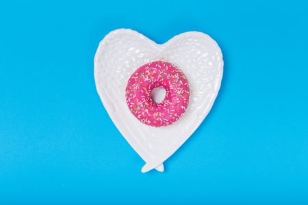 Heart form white plate with donut on blue backgroundの写真素材