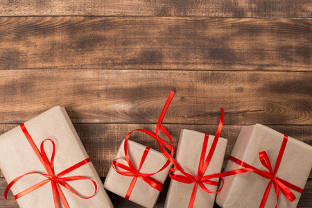 Gifts with red ribbon on the wooden table. Vintage gift box on wooden board with space for text.の写真素材