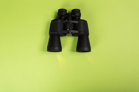 Black binoculars with orange lens on green backgroundの写真素材