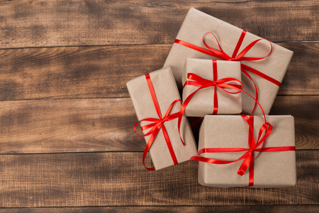 Gifts with red ribbon on the wooden table. Vintage gift box on wooden board with space for text.の写真素材