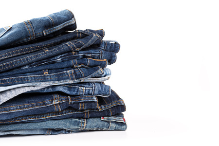 stack of various shades of blue jeans on white backgroundの写真素材