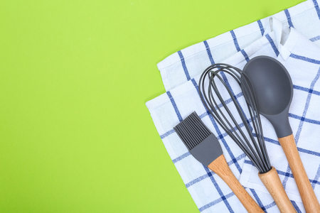 Set of kitchen utensils with wooden handles and checkered towel on a green backgroundの写真素材