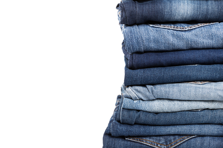 stack of various shades of blue jeans on white backgroundの写真素材