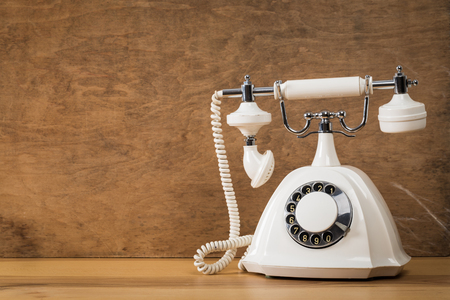 Vintage old white telephone on wooden table with color wall backgroundの写真素材