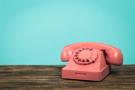 Vintage old telephone on wood table with turquoise wall backgroundの写真素材