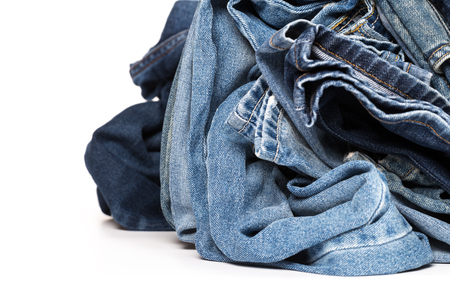 stack of various shades of blue jeans on white backgroundの写真素材