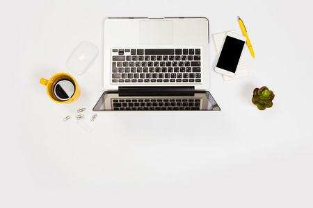 Modern workspace with coffee cup, smartphone, paper, notebook, tablet and laptop copy space on white color background. Top view. Flat lay style.の写真素材