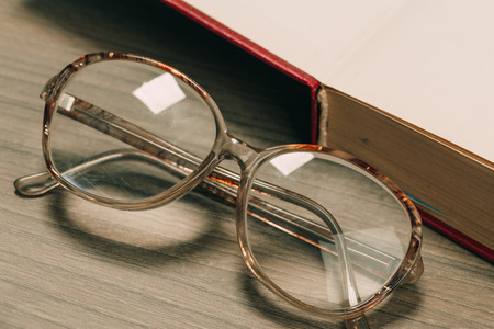 old book open on a wooden table with glassesの写真素材