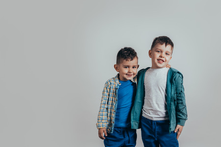 Photo of two adorable boys brothers or friends embracing and smiling joyfully on a gray background. Vintage colorの写真素材