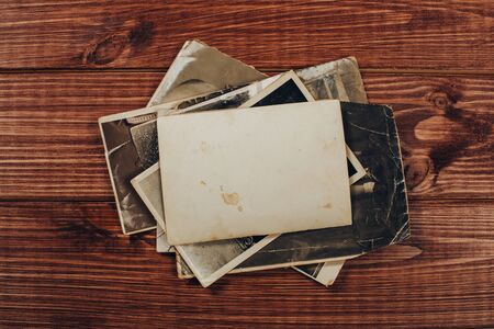 Stack old photos on table. Mock-up blank paper. Postcard rumpled and dirty vintage. Retro cardの写真素材