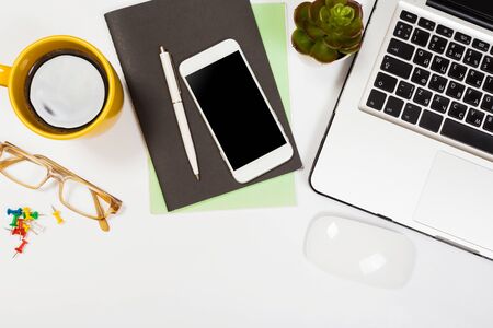 Modern workspace with coffee cup, smartphone, paper, notebook, tablet and laptop copy space on white color background. Top view. Flat lay style.の写真素材