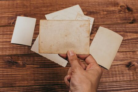 Stack old photos on table. Mock-up blank paper. Postcard rumpled and dirty vintage. Retro cardの写真素材