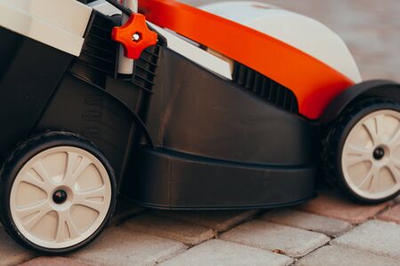 new electric lawn mower on the tile near the garden. toned photoの写真素材