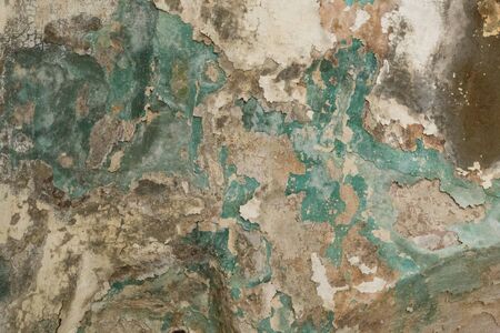Brick wall. Old flaky white paint peeling off a grungy cracked wall. Cracks, scrapes, peeling old paint and plaster on background of old cement wall. An old cement stone wall as vintage cracked.の写真素材
