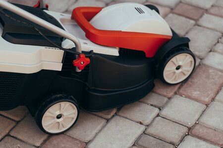 new electric lawn mower on the tile near the garden. toned photoの写真素材