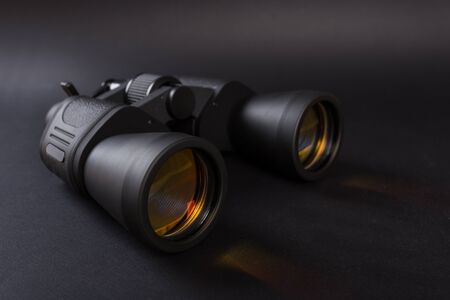 Black binoculars with orange lens on dark backgroundの写真素材