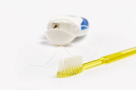 Dental floss and toothbrush on a white background.の写真素材