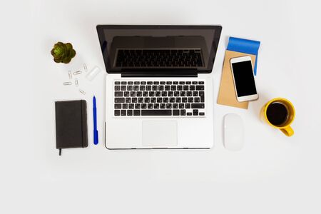 Modern workspace with coffee cup, smartphone, paper, notebook, tablet and laptop copy space on white color background. Top view. Flat lay style.の写真素材