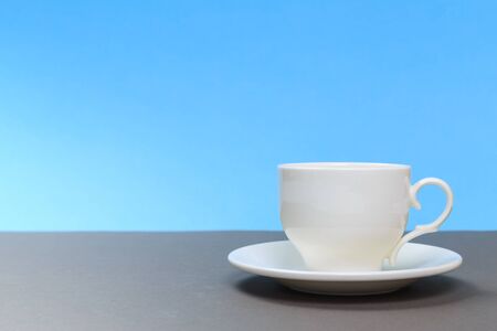 classic  white porcelain tea cup on gray board and blue background