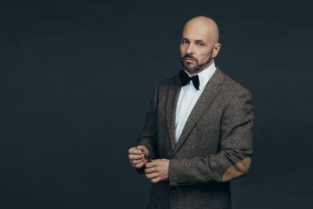 Serious middle aged man with a deadpan face expression dressed in casual posing on a dark gray background with copy spaceの写真素材