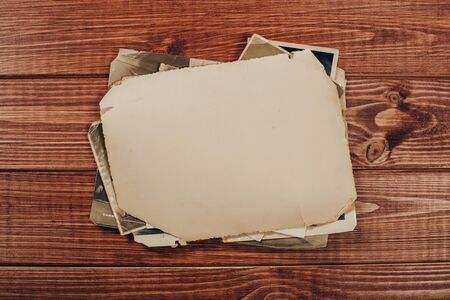 Stack old photos on table. Mock-up blank paper. Postcard rumpled and dirty vintage. Retro cardの写真素材